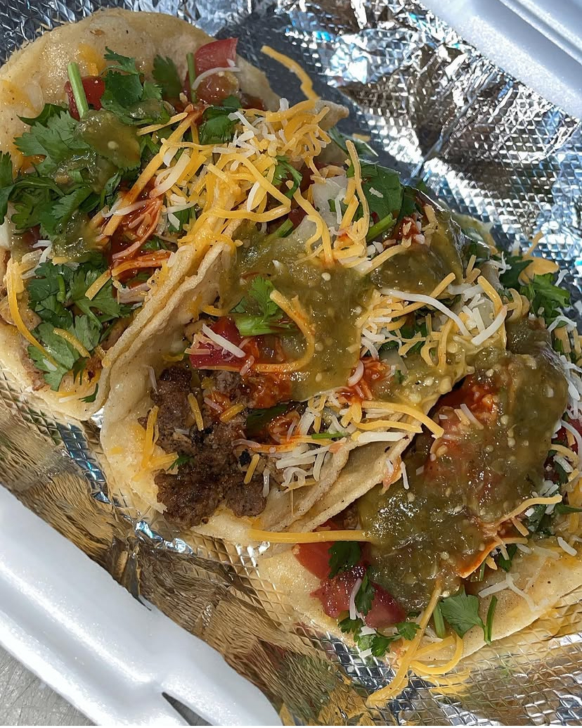 Loaded tacos with cheese, cilantro, and green sauce